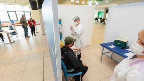 Healthcare worker administering COVID 19 vaccine in Ukraine vaccination center representing national rollout progress in 2021