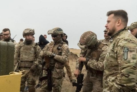 Andriy Biletsky in military gear speaking about needing 9,000 troops and equipment to break the Mariupol blockade during the Ukraine war.