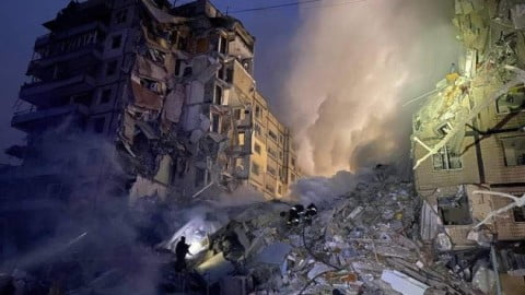 Aftermath of massive Russian missile strike on Dnipro with damaged buildings, emergency responders and smoke rising over the city’s destroyed infrastructure.