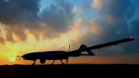 Bayraktar TB2 drone being shot down by Kyiv air defence after losing control, burst of fire and smoke over city skyline at dusk