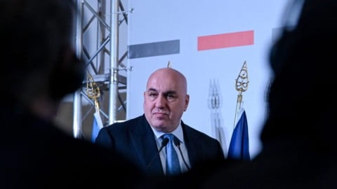 Italian and Ukrainian flags with military hardware backdrop symbolize Italy’s cautious stance on future Ukraine military aid amid debate over unlimited support.