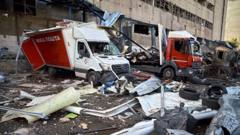 Destroyed postal terminal in Kharkiv after Russian missile and drone strike, with burned trucks, debris and smoke covering the logistics facility.