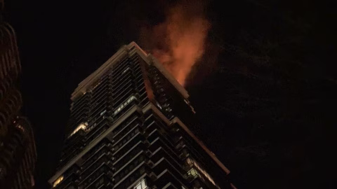 Damaged residential tower in Kyiv hit by a Russian drone where the Estonian ambassador’s residence is located, smoke rising and emergency crews on site.