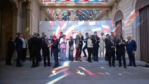 World leaders and Ukrainian, U.S., and European representatives at a Paris summit table discussing ceasefire plans and security guarantees for Ukraine.