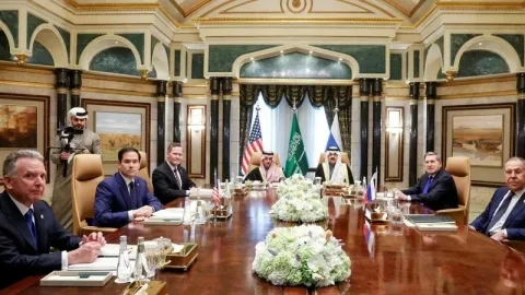 Meeting table with flags of Russia and the United States and rare‑earth metals samples symbolizing emerging talks on strategic mineral cooperation.