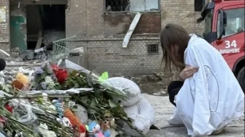 Grieving Ukrainian parents holding photo of their children killed by a missile strike — the human cost of war and urgent appeal for support.