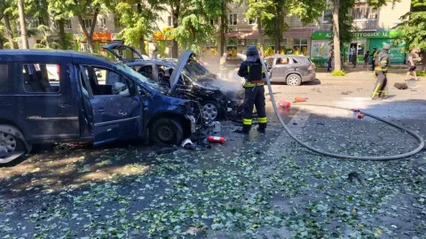 Damaged cars smolder in the center of Sumy after Russian strike with emergency responders and debris on city street