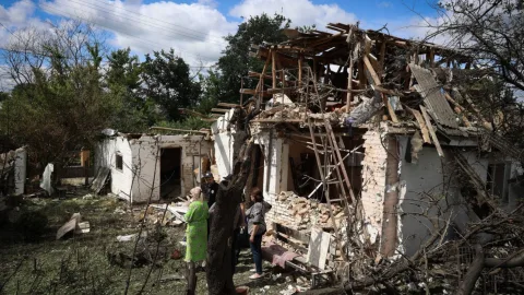 Damaged hospital and emergency responders in the Kyiv region after a Russian air strike, with smoke and fire as civilians are evacuated.