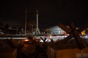 Maidan Nezalezhnosti in central Kyiv during a blackout, darkened streets and silhouettes symbolizing war, energy collapse, and resilience