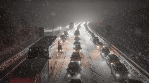 Heavy snowfall in southwestern Germany with snow‑covered road, stalled cars, delayed trains and winter air traffic disruption near Stuttgart.