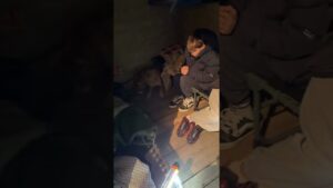 Ukrainian civilians standing near destroyed buildings after Russian missile strike, reflecting grief and wartime trauma