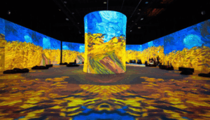 Visitors inside immersive Van Gogh exhibition with large-scale projections of paintings surrounding walls and floor in a digital art space